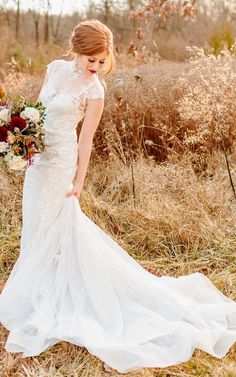 a woman in a wedding dress is standing in the grass with her hand on her hip