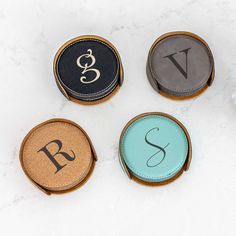 four personalized leather coasters with monogrammed letters on them sitting on a marble surface