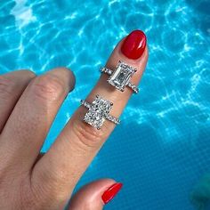 a woman's hand with three different rings on it next to a swimming pool