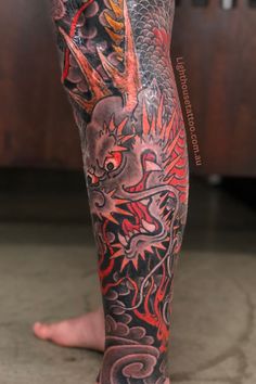 a man's leg with tattoos on it and a dragon in the middle of his leg