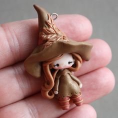 a tiny doll is wearing a brown hat and dress with a long tail on it's head