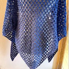 a blue crocheted shawl hanging on a hook in front of a mirror