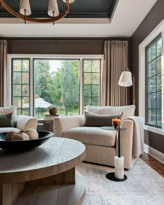 a living room with two couches and a table in front of large windows that look out onto the trees