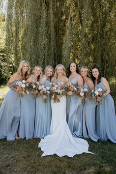 a group of women standing next to each other in front of a tree with flowers