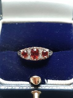 A vintage 9ct gold garnet and diamond ring. The ring is Hallmarked 9ct gold. The largest oval cut garnet is claw set at the centre and measures 5 x 4mms. The outside garnets each measure 4 x 3mm's. Flanking the central garnet on both sides are two round brilliant cut diamonds. These four diamonds have an estimated combined weight of 0.08ct's. Finger size N, but we can make the ring bigger, or smaller. Victorian Oval Red Diamond Ring, Victorian Style Red Oval Diamond Ring, Hallmarked Red Oval Sapphire Ring, Hallmarked Oval Red Sapphire Ring, Antique Red Oval Diamond Ring, Antique Oval Red Diamond Ring, Vintage Oval Garnet Birthstone Ring, Vintage Oval Three-stone Ruby Ring, Opal Drop Earrings