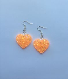 "Each pair of resin earrings are handmade to order, therefore no two pairs are identical! Each item is slightly unique and one of a kind. However, I try to get as close as possible :) Made with nickel free, hypoallergenic, sterling silver fish hooks.  Heart width is approximately 1.25\", and is made with epoxy resin, orange glow pigment, and chunky iridescent glitter with stars ✨ These neon orange heart earrings glow in the dark AND are ultraviolet blacklight reactive! Perfect for raves, parties Heart Shaped Resin Jewelry For Party, Heart-shaped Resin Earrings For Party, Cute Orange Jewelry For Party, Cute Orange Party Jewelry, Handmade Heart-shaped Resin Earrings, Orange Resin Jewelry For Party, Glow Heart, Neon Earrings, Rave Jewelry