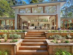 a modern house with wooden steps leading to the front door and living room in the background