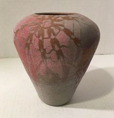 a pink and brown vase sitting on top of a white table