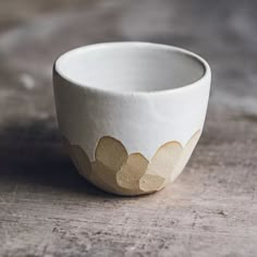 a white and gold bowl sitting on top of a wooden table