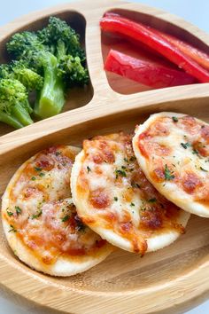 three small pizzas on a wooden plate with broccoli