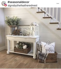 there is a white table with some plants on it next to a stair case and pillows