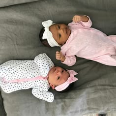 two baby dolls laying next to each other on a bed