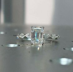 an emerald cut diamond engagement ring on a table