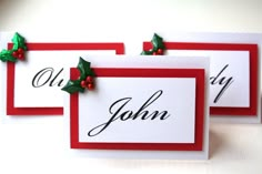 three christmas place cards with holly leaves and red ribbon on them, one is for john