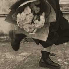 a person in black boots is holding some kind of bag with something white on it