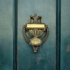 an ornate brass door handle on a green painted door with gold accents and a plaque above it