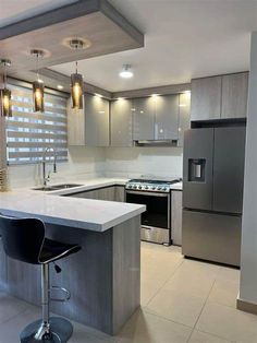 a modern kitchen with stainless steel appliances and marble counter tops, along with white tile flooring