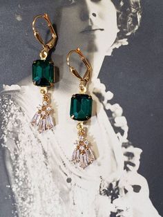 These Art Deco style earrings are inspired by the gorgeous emerald and diamond jewelry worn during the 1920s. Sparkling clear rhinestone pendants dangle from emerald green rhinestone connectors. The earrings measure 1 3/4 inches long and hang from gold plated lever back ear wires. These elegant dangles are reminiscent of the geometric shaped rhinestone jewelry worn during the Jazz Age. Perfect for a Great Gatsby themed wedding or party. ABOUT THIS COLLECTION The sophisticated style of the Roarin Vintage Emerald Earrings For Anniversary, Art Deco Dangle Jewelry For Party, Classic Evening Emerald Jewelry, Classic Emerald Jewelry For Evening, Art Deco Dangle Party Jewelry, Art Deco Drop Earrings For Evening, Art Deco Dangle Earrings For Vintage Events, Victorian Style Drop Earrings For Party, Art Deco Green Jewelry For Pierced Ears