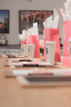 coffee cups are lined up on the table in front of paper bags and pencils