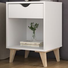 a white nightstand with a plant and books on it