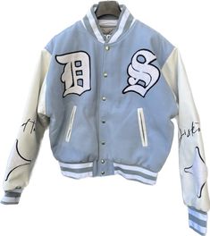 A varsity bomber jacket is a type of outerwear that is typically associated with American collegiate and sports culture. It draws inspiration from traditional letterman jackets worn by varsity athletes. The jacket is characterized by its casual and athletic design, often featuring a snap-button front closure, ribbed collar, cuffs, and waistband. The varsity bomber jacket is usually made of durable materials such as wool or nylon, providing warmth and protection from the elements. The body of the White Varsity Jacket With Embroidered Logo For Streetwear, Varsity Outerwear With Baseball Collar, Cotton Track Jacket With Embroidered Logo For Streetwear, Long Sleeve Varsity Jacket With Letter Embroidery For Streetwear, White Varsity Outerwear With Embroidered Logo, Varsity Jacket For College In Winter, Winter Varsity Jacket For College, Varsity Jacket With Letter Embroidery, Blue Outerwear With Embroidered Logo For College