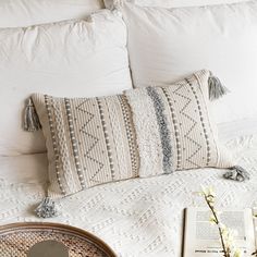 a bed with pillows and a book on top of it next to a vase filled with flowers