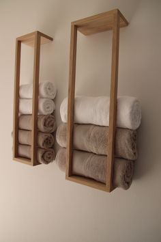 two wooden shelves holding folded towels and folded towel rolls in front of each other on the wall