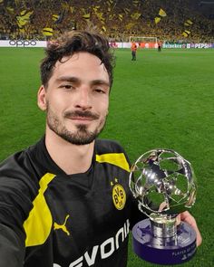 a man holding up a trophy on top of a soccer field