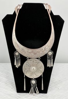 "Vintage Thailand Collar Necklace/Etched Floral/Silver Platted/12\" L x 5 1/2\". Stunning Vintage Hmong Miao Torque silver necklace . Silver plate brass ceremonial Torque Necklace with fringe & bells. Hand engraved with botanical scroll motif & elongated links. Hangs and moves beautifully, the bib fits with hook closure. Good vintage condition, the few areas that are showing age are some of the silver around the neck area is faded and the two top dangling flowers are pushed in. Please see pictures for full details. Miao silver is not pure silver, but an alloy of silver, copper and nickel. It's a traditional material for making jewelry by craftsmen of Miao Hmong ethnic tribe. Necklace hangs: 12\" long x 5 1/2\" wide" Silver Metal Necklace For Ceremonial Occasions, Artisan Silver Etched Necklace, Ceremonial Silver Medallion Jewelry, Ceremonial Silver Etched Necklace, Ceremonial Etched Silver Necklace, Silver Large Pendant Jewelry For Festival, Festival Silver Jewelry With Large Pendant, Ceremonial Silver Medallion Necklace, Silver Medallion Necklace For Ceremonial