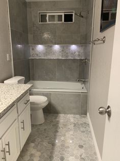 a white toilet sitting next to a bath tub in a bathroom