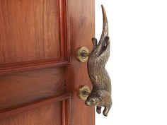 a door handle on a wooden door with a cat figurine hanging from it's side