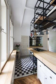 a kitchen with black and white checkered flooring next to an open staircase case