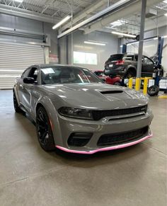 a grey car with pink stripes parked in a garage