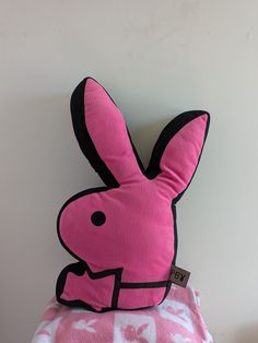 a pink stuffed animal sitting on top of a blanket next to a white and black wall