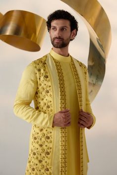 Summer Love Shrug Set | Jatin Malik Introducing our vibrant lemon yellow shrug set, adorned with intricate floral hand embroidery and three types of embroidered lapels in shades of yellow. This ensemble radiates freshness and sophistication, capturing attention with its intricate detailing and vibrant color palette. Paired with an embroidered shoulder-button kurta and tapered trousers, this outfit offers a perfect balance of elegance and contemporary style. Ideal for special occasions, this ensemble is sure to make a statement with its unique design and impeccable craftsmanship. Included in purchase: Shrug Set, Kurta, Trousers Product Specification Color: Yellow Fabric: Linen Silk Occasion: Engagement, Wedding, Bridal, Reception Style: Shrug Set, Kurta, Trousers Care: Dry Clean Work: Hand Designer Yellow Sets With Chikankari Embroidery, Yellow Sets With Chikankari Embroidery, Transitional Designer Wear Yellow Sherwani, Traditional Yellow Sherwani For Designer Wear, Yellow Bandhgala With Zari Work For Designer Wear, Designer Yellow Sherwani For Eid, Yellow Embroidered Kurta For Reception, Designer Yellow Sherwani For Diwali, Festive Yellow Designer Bandhgala