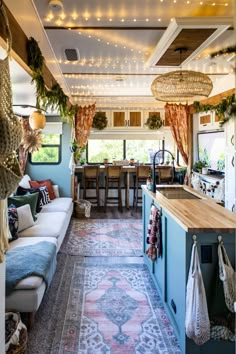 a living room filled with furniture and lots of christmas lights hanging from the ceiling next to a kitchen