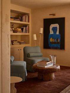 a living room with two blue chairs and a coffee table in front of a book shelf