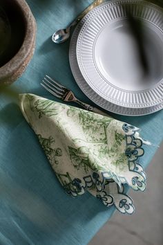 a table set with plates, silverware and napkins