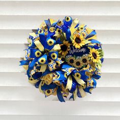 a blue and yellow sunflower wreath with the word welcome written on it in black lettering