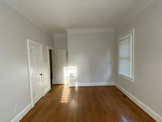 an empty room with hard wood floors and white walls