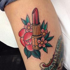 a woman's leg with a tattoo on it that has a lipstick and flowers on it