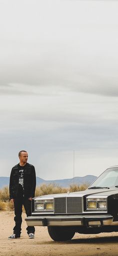 a man standing next to a car in the desert