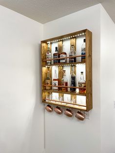 a wooden shelf filled with lots of bottles on top of a white wall next to a mirror