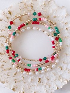 This very dainty Christmas set can be purchased as a set or individually  There are four pieces in this set. Two seed bead and gold filled beads bracelets, one pearl bracelet and Czech (three beads) and gold filled beads. Christmas Glass Bead Bracelet, Christmas Stretch Bracelets, Fun Beaded Bracelets, Diy Holiday Jewelry, Christmas Stack Bracelets, Glass Bead Bracelet Designs, Christmas Bracelets Clay Beads, Bracelet Words Ideas, Holiday Beaded Bracelets