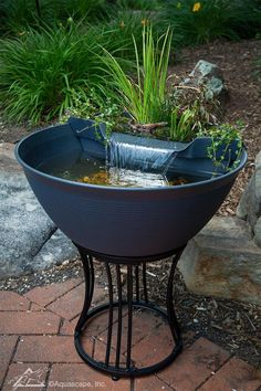 a planter filled with water sitting on top of a brick walkway