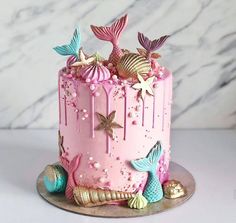 a pink cake decorated with mermaid decorations