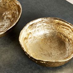 two gold bowls sitting on top of a table