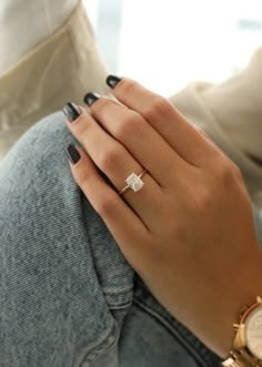 a woman's hand with a ring on her finger and a watch in the other hand