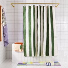 a green and white striped shower curtain in a bathroom with tile flooring on the walls