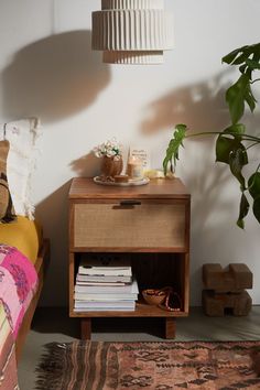 a bedroom with a bed, nightstand and plant on the side table next to it